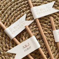 brown  cream and gold foil paper straw flags for engagement party with we're engaged on the front