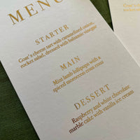 white card and gold foil text menu card for place settings