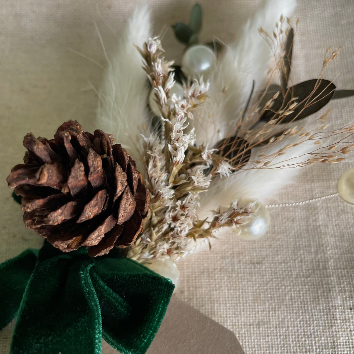 decorative mini dried flower bouquet for christmas dinner with pine cones and green velvet ribbon