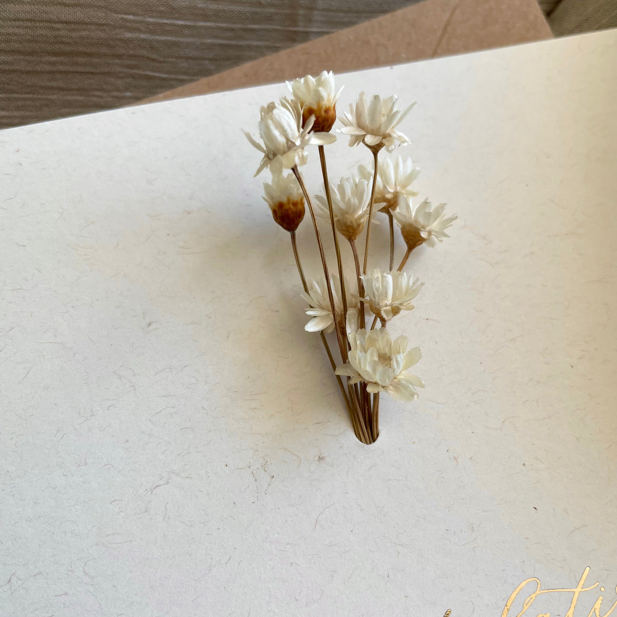 Small bouquet of dried flowers on ivory engagement card