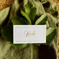 flat rectangular white place card foiled in elegant cursive script with gold border for place settings