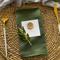 gold foil name cards on white card with gold wax seal with foliage design for rustic wedding styles.