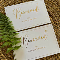 gold foil and white reserved cards personalised with guests names for elegant wedding ceremony