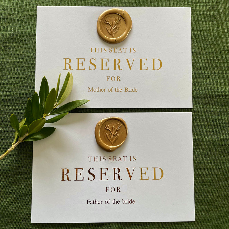 this seat is reserved for cards for wedding ceremony seating on white card, gold foil with a gold wax seal