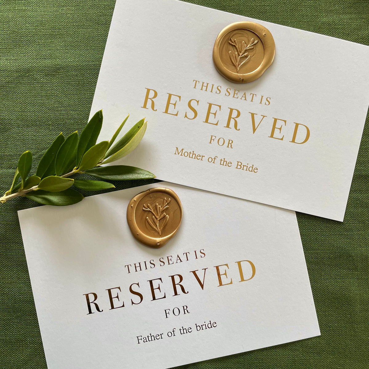 reserved seat signs for wedding ceremony on white card, names in gold foil text with a gold wax seal
