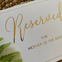 close up of gold foil on white reserved seating cards for wedding ceremony
