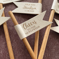 Rustic wedding-themed paper drink straws flags with personalised text on the back. cheers to the newlyweds on the front of the flag in bronze foil.
