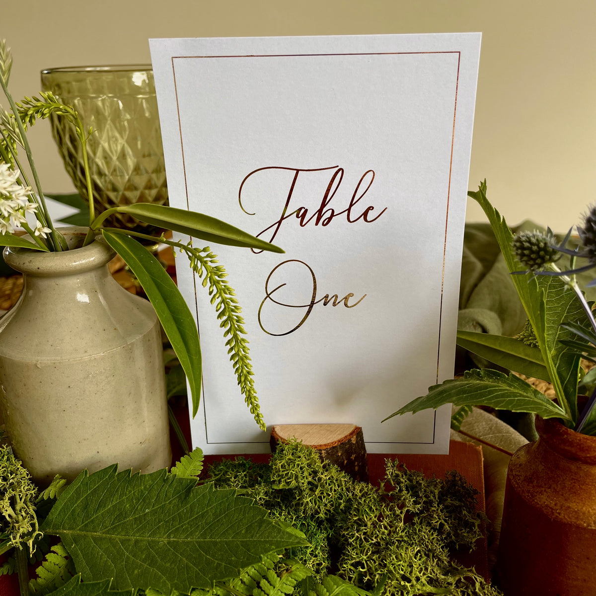 a white table number card with gold foil script and border for elegant wedding style